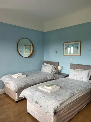 two beds in a room with blue walls at Bowood Park Hotel in Camelford