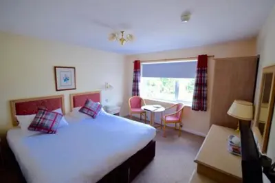 a hotel room with a large bed and a table at Penmere Manor Hotel in Falmouth