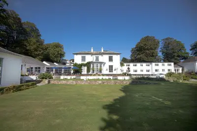 a large white house with a large yard at Penmere Manor Hotel in Falmouth