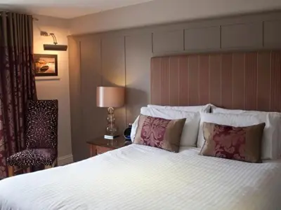 a hotel room with a large bed and a chair at The Norway Inn in Perranwell