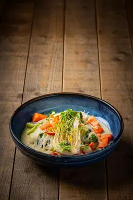 a blue bowl of soup with vegetables and noodles at The Norway Inn in Perranwell