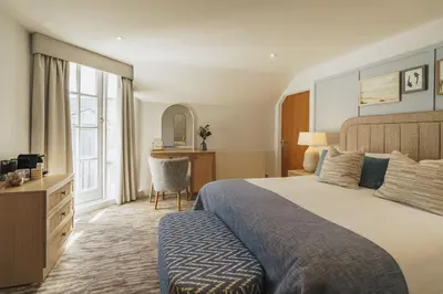 a bedroom with a large bed and a desk at The Old Quay House Hotel in Fowey