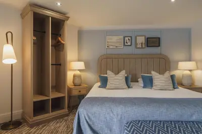 a bedroom with a large bed with blue sheets and pillows at The Old Quay House Hotel in Fowey