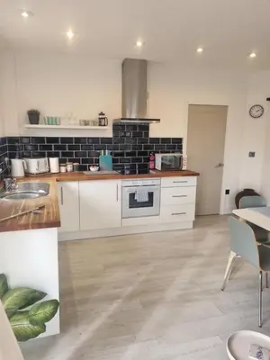 a kitchen with white cabinets and a black brick wall at Halwyn View in St Austell