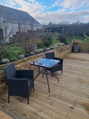 a patio with a table and chairs on a wooden deck at Halwyn View in St Austell