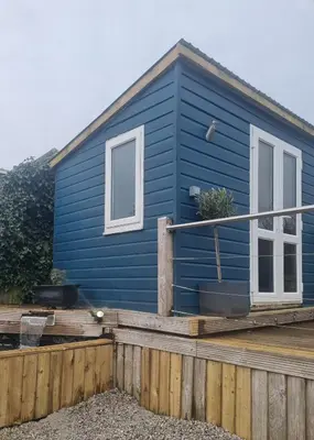 a blue tiny house with a wooden deck at Halwyn View in St Austell