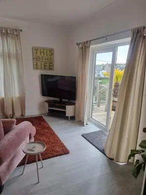 a living room with a tv and a sliding glass door at Halwyn View in St Austell