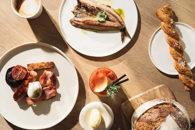 a table topped with plates of food and bread at Scarlet Hotel - Adults Only in Mawgan Porth