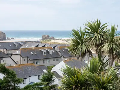a group of houses and palm trees next to the beach at Lyndhurst in Perranporth
