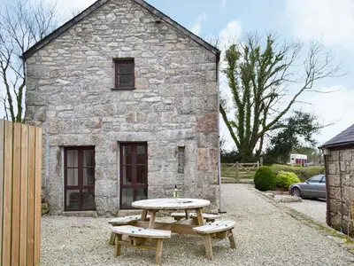 a picnic table in front of a stone building at Trevellyan Barn in Lanivet