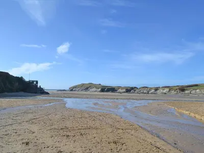 a beach with some water on the sand at Little Lookover in Saint Columb Minor