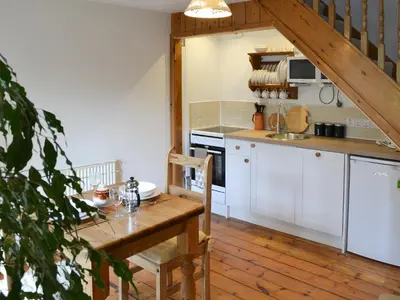a kitchen with white cabinets and a wooden table at Little Lookover in Saint Columb Minor