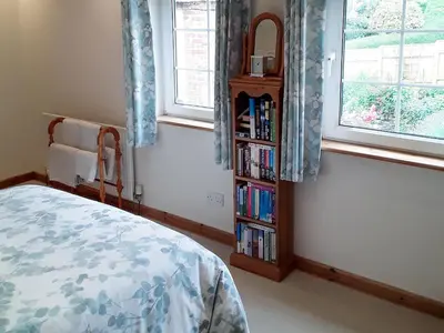 a bedroom with a bed and a book shelf with books at Little Lookover in Saint Columb Minor
