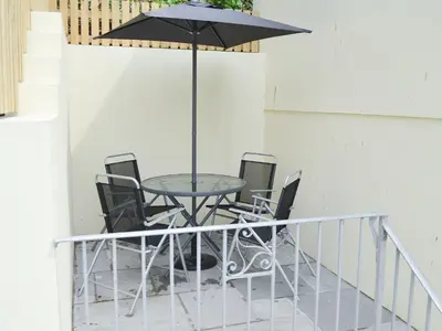 a table with chairs and an umbrella on a balcony at Knights Den in Port Isaac
