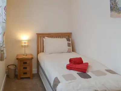 a bedroom with a bed with a red object on it at Knights Den in Port Isaac