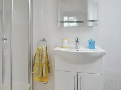 a white bathroom with a sink and a shower at Penfose Apartment in Mevagissey