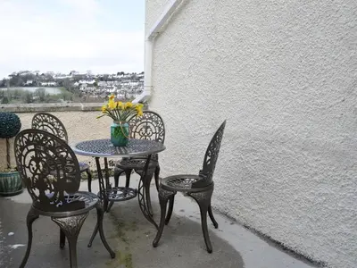 a table and chairs with a vase of flowers on a patio at Penfose Apartment in Mevagissey