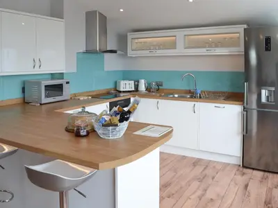 a kitchen with white cabinets and a wooden counter top at Penfose Apartment in Mevagissey