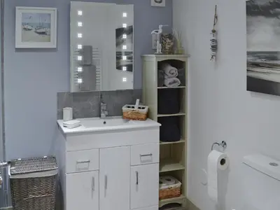 a white bathroom with a sink and a mirror at Little Tregarthen in Padstow