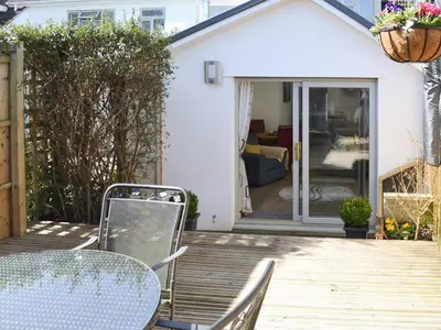 a patio with a table and chairs on a deck at Little Tregarthen in Padstow