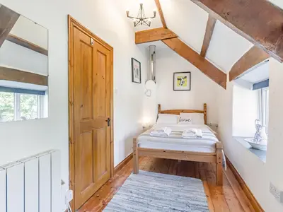 a bedroom with a bed and a wooden door at Jarvies Cottage in Boscastle