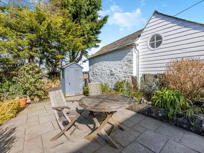 a patio with a wooden table and two chairs at Jarvies Cottage in Boscastle