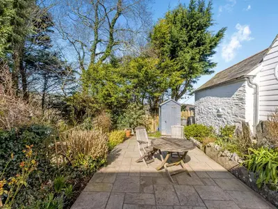 a patio with a table and chairs in a garden at Jarvies Cottage in Boscastle