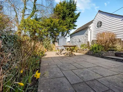 a patio with a table and chairs next to a building at Jarvies Cottage in Boscastle