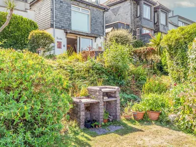 a house with a stone fireplace in the yard at Studio Sea Urchin in Carbis Bay