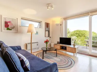 a living room with a blue couch and a tv at Studio Sea Urchin in Carbis Bay