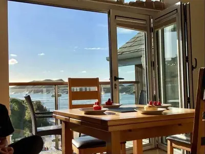 a dining room table with a view of the ocean at Porth Sands Beachfront Apartment in Newquay