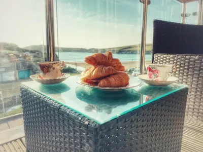 a table with a plate of croissants and two cups at Porth Sands Beachfront Apartment in Newquay