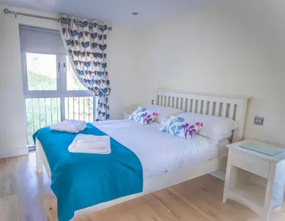 a bedroom with a white bed and a window at Porth Sands Beachfront Apartment in Newquay