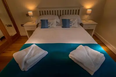 a bedroom with a bed with white sheets and pillows at Porth Sands Beachfront Apartment in Newquay