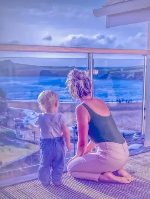 a woman and a child looking out at the ocean at Porth Sands Beachfront Apartment in Newquay
