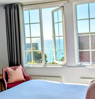 a bedroom with windows and a bed and a chair at The Westcott by the Sea - Just for Adults in Falmouth