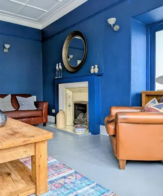 a living room with blue walls and a mirror at The Westcott by the Sea - Just for Adults in Falmouth