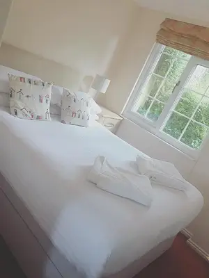 a white bed with white pillows and a window at Camellia Chalet in Germoe