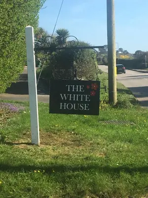 a sign for a white house on the side of a road at Camellia Chalet in Germoe