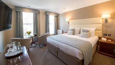 a hotel room with a large bed and a desk at The Carlyon Bay Hotel and Spa in St Austell