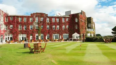 a large brick building with red ivy on it at The Carlyon Bay Hotel and Spa in St Austell