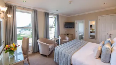 a hotel room with a bed and a desk and windows at The Carlyon Bay Hotel and Spa in St Austell