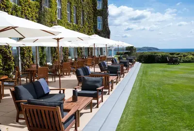a row of chairs and umbrellas on a patio at The Carlyon Bay Hotel and Spa in St Austell