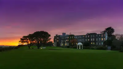 a building on a golf course at sunset at The Carlyon Bay Hotel and Spa in St Austell