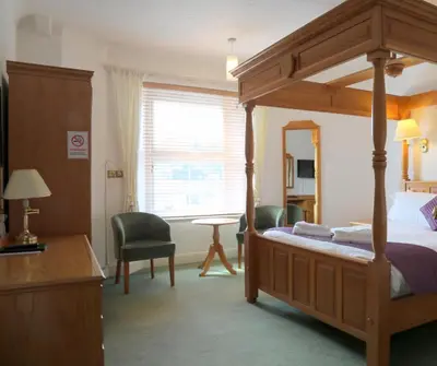 a bedroom with a canopy bed and a desk at Westberry Hotel in Bodmin