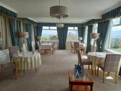 a dining room with tables and chairs and windows at Trelawne Hotel in Falmouth