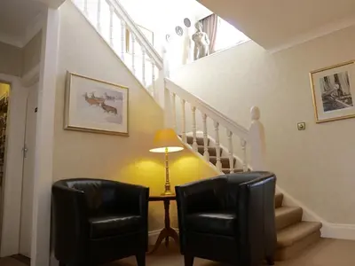 a hallway with two chairs and a table and stairs at Trelawne Hotel in Falmouth