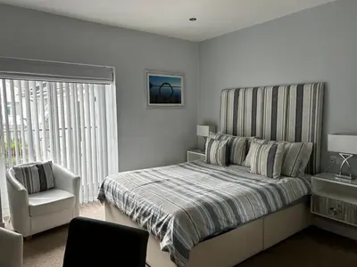 a bedroom with a bed and a chair and a window at Wenden Guest House in Newquay
