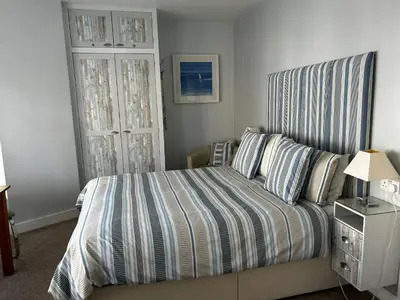 a bedroom with a bed with a striped headboard at Wenden Guest House in Newquay