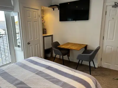 a bedroom with a bed and a table and a television at Wenden Guest House in Newquay
